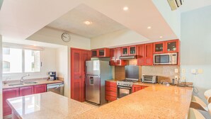 Una cocina con encimeras de granito, electrodomésticos de acero inoxidable y armarios rojos.