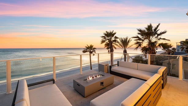 A balcony with a sofa, a fire pit, and palm trees overlooking a beach at sunset. - 'Domus Pacis' | Two Pools, Beach Front,  Next to Seaside 30A (Seagrove Beach)