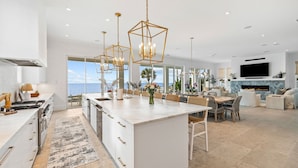 A modern kitchen with a large island, white cabinetry, and a view of the ocean. - 'Domus Pacis' | Two Pools, Beach Front,  Next to Seaside 30A (Seagrove Beach)