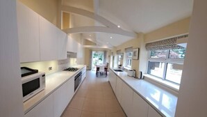 A modern kitchen with white cabinets, a gas stove, and a microwave. - Stunning 3BD Victorian House in Bramhall Village (Bramhall)
