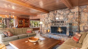 A cozy living room with a stone fireplace, wooden ceiling beams, and a comfortable seating area. - River's Edge w/ BBQ, Wifi, Firepit! (Yosemite National Park)