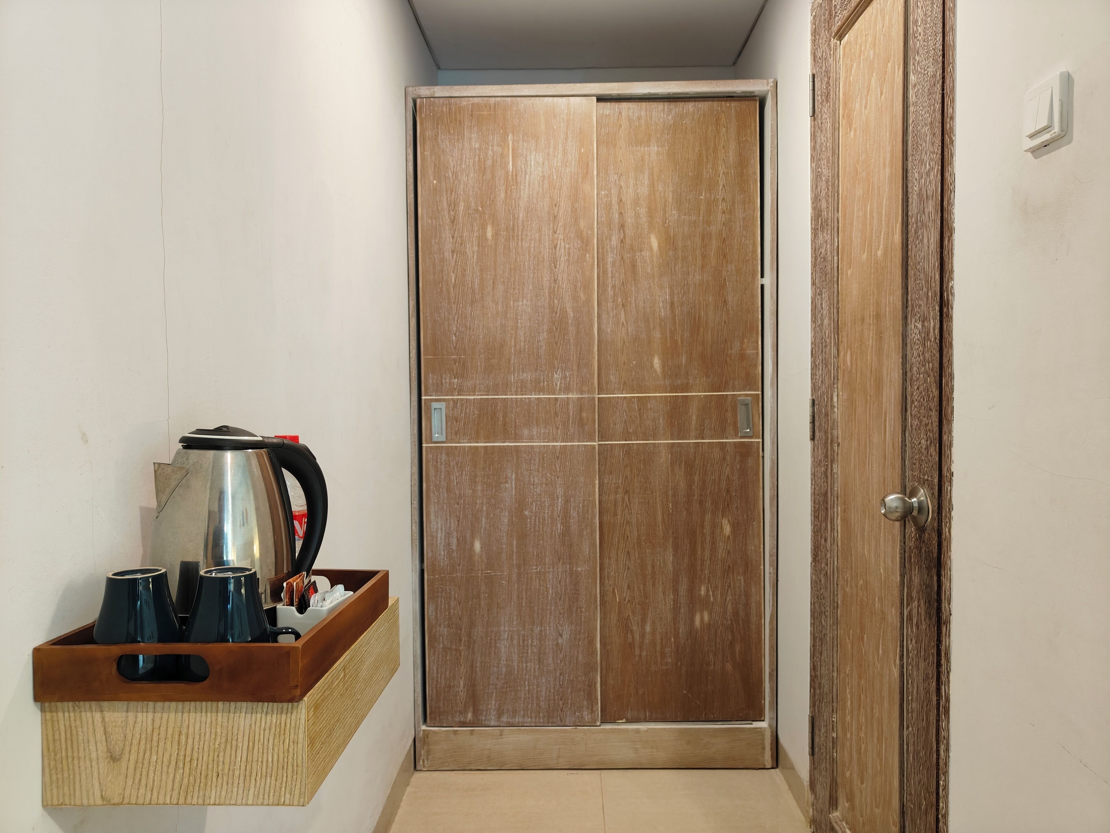 Un pasillo con un armario de madera, una tetera y una bandeja con tazas y un cebrero.