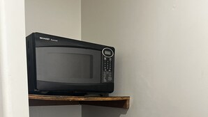 A microwave and a refrigerator in a kitchen. - Grand Howell Inn (Howell)