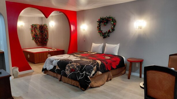 A bedroom with a large bed, a heart-shaped wall, and a decorative wreath. - Grand Howell Inn (Howell)