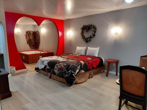 A bedroom with a large bed, a heart-shaped wall, and a decorative wreath. - Grand Howell Inn (Howell)