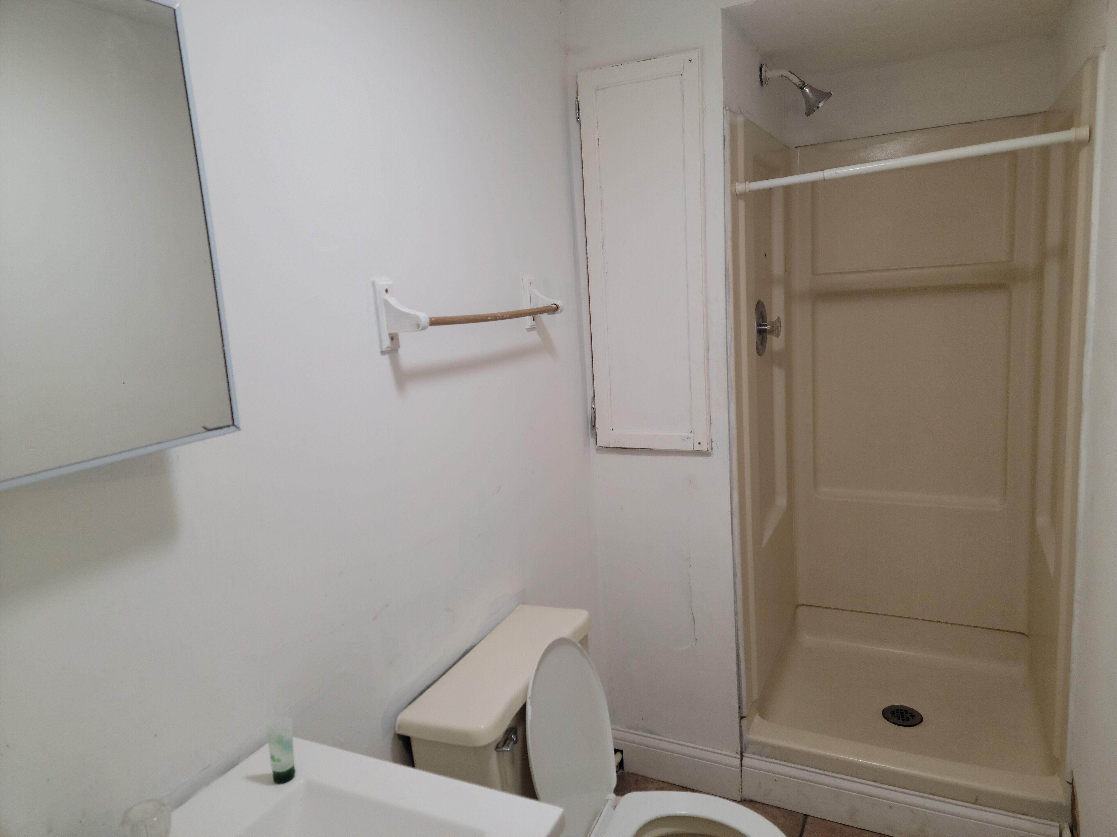 A small bathroom with a toilet, a sink, and a shower stall.