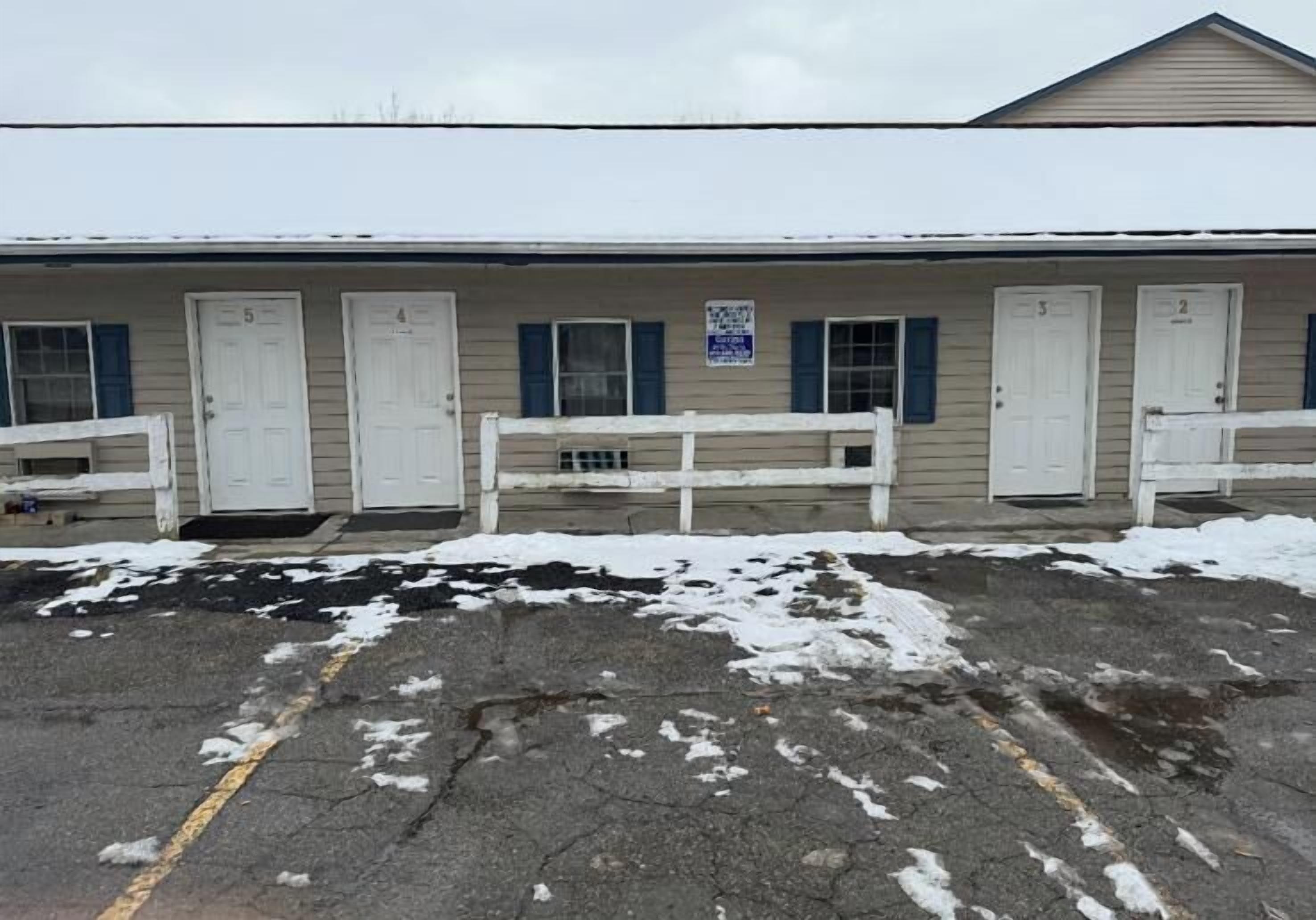 A motel with numbered rooms, a covered parking area, and a sign indicating no smoking.