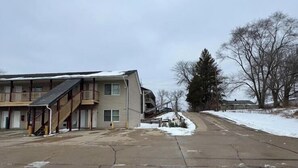 A multi-story motel with a covered outdoor area and a staircase leading to the entrance. - Grand Howell Inn (Howell)