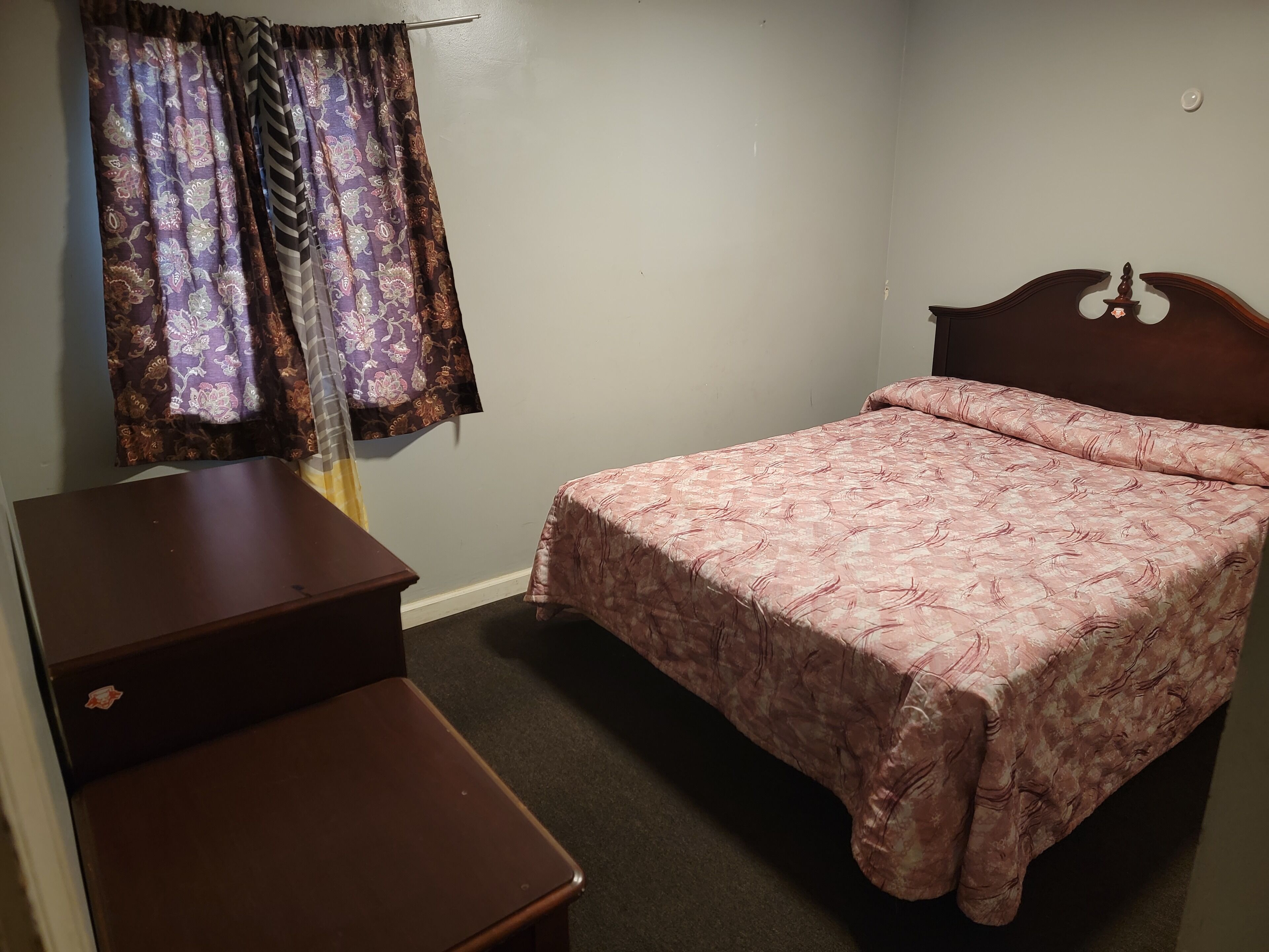 A bedroom with a bed, a dresser, and a nightstand.