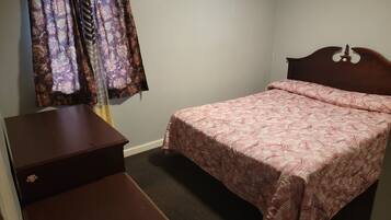 A bedroom with a bed, a dresser, and a nightstand.