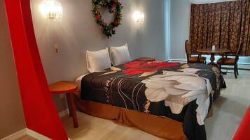 Een hotelkamer met een bed, een kleine tafel, een stoel, een eettafel en een decoratieve krans aan de muur.