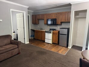 A compact kitchen with wooden cabinets, a microwave, a stove, and a refrigerator.