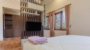 A bedroom with a bed, a TV, a wooden wardrobe, and a window with curtains. - Bait Nahwa  (Narmada)