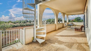 A covered outdoor area with a spiral staircase, a seating area with a table and chairs, and a view of the surrounding landscape. - 3 bedroom lovely home in Santa Croce Camerina (Santa Croce Camerina)
