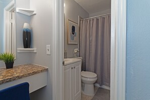 A bathroom with a toilet, sink, and shower curtain. - Studio @ Montrose 01! Downtown, Medical Center, Stadium (Houston)