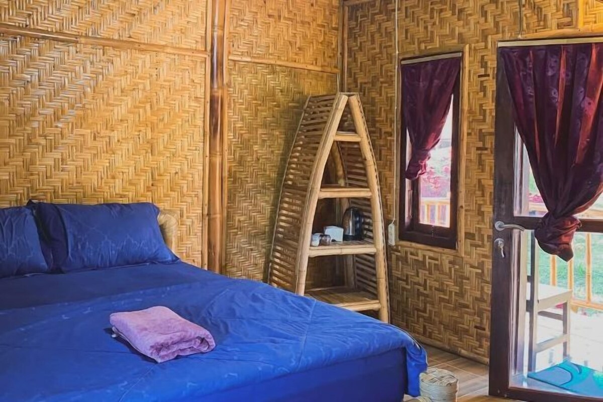A room with a bed, a wooden ladder shelf, and a window with curtains.