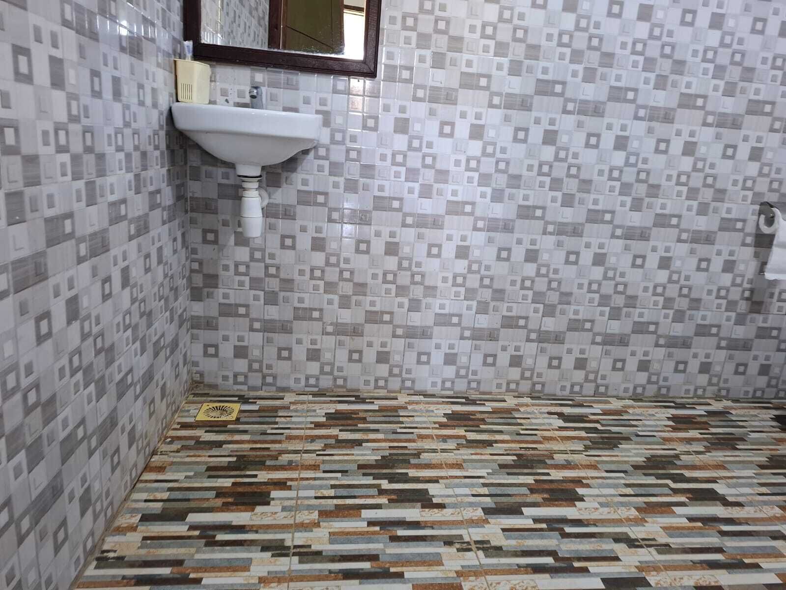 Casa de banho com chão em azulejos, pia e espelho.