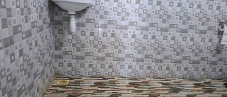Un baño con piso de baldosas, un lavamanos y un espejo.