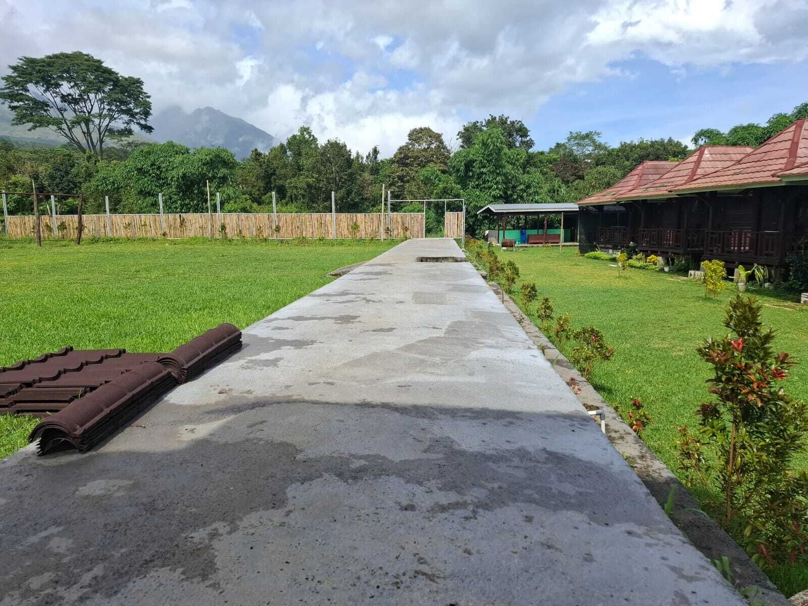 A pathway leading to a building with a red roof, surrounded by a well-maintained lawn and trees.