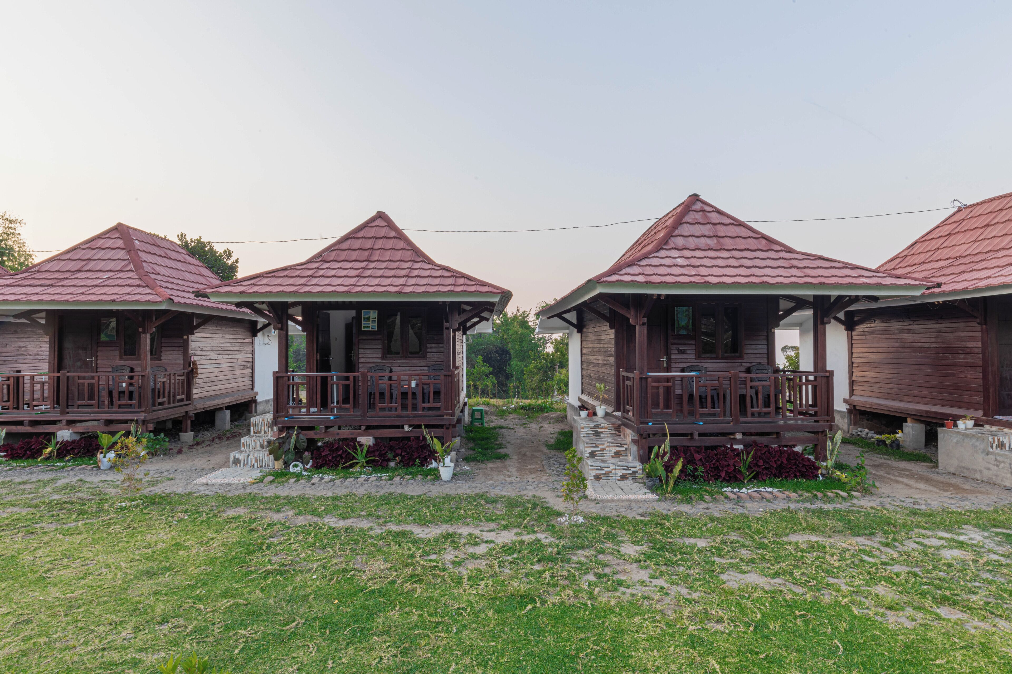 A row of wooden cabins with pitched roofs and wooden balconies, connected by a pathway.