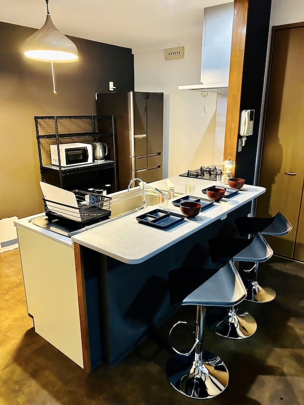 A modern kitchen with a central island, bar stools, a microwave, and a gas stove.