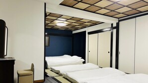 A hotel room with a bed, a small seating area, and a wardrobe. - Matsuyamachi Dotonbori Condo (Osaka)