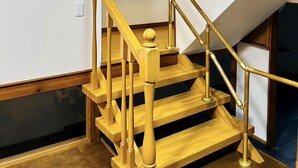 A wooden staircase with a handrail and a light fixture above. - Matsuyamachi Dotonbori Condo (Osaka)