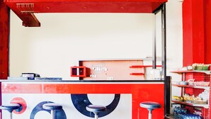 A red and white counter with a cash register, a menu board, and three bar stools. - OYO Life 93290 Homestay Betro Syariah (Sidoarjo)