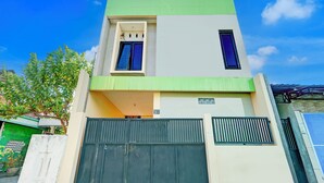 A modern two-story building with a green roof, a large garage door, and a small window on the upper floor. - OYO Life 93290 Homestay Betro Syariah (Sidoarjo)