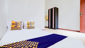 A hotel room with a neatly made bed, a blue and yellow patterned throw, and a wardrobe against the wall. - OYO Life 93290 Homestay Betro Syariah (Sidoarjo)