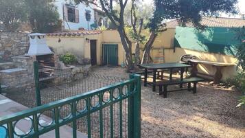 Un'area patio con un barbecue in pietra, posti a sedere all'aperto e una piscina.