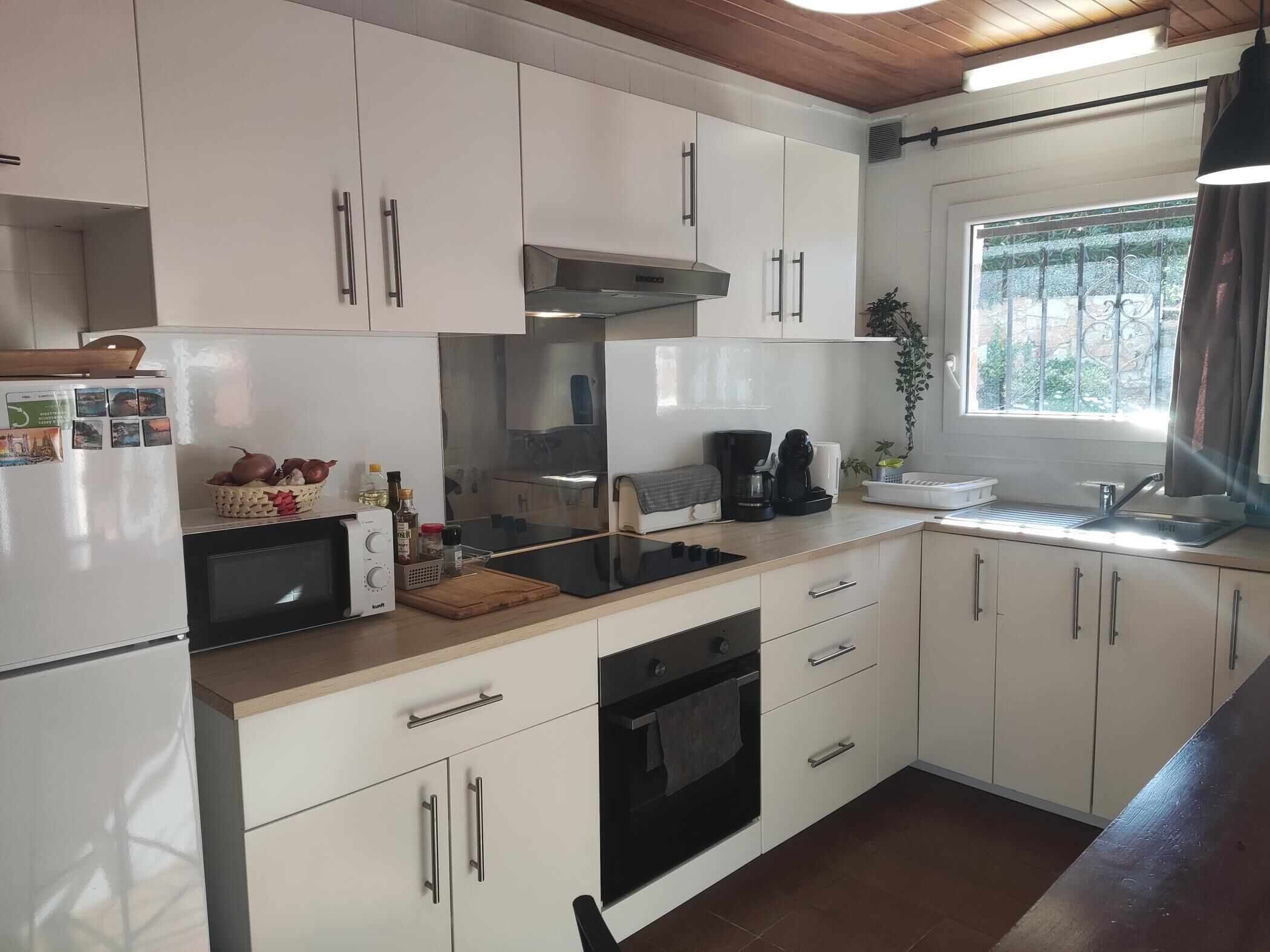 A modern kitchen with white cabinets, a built-in oven, a microwave, and a coffee maker.