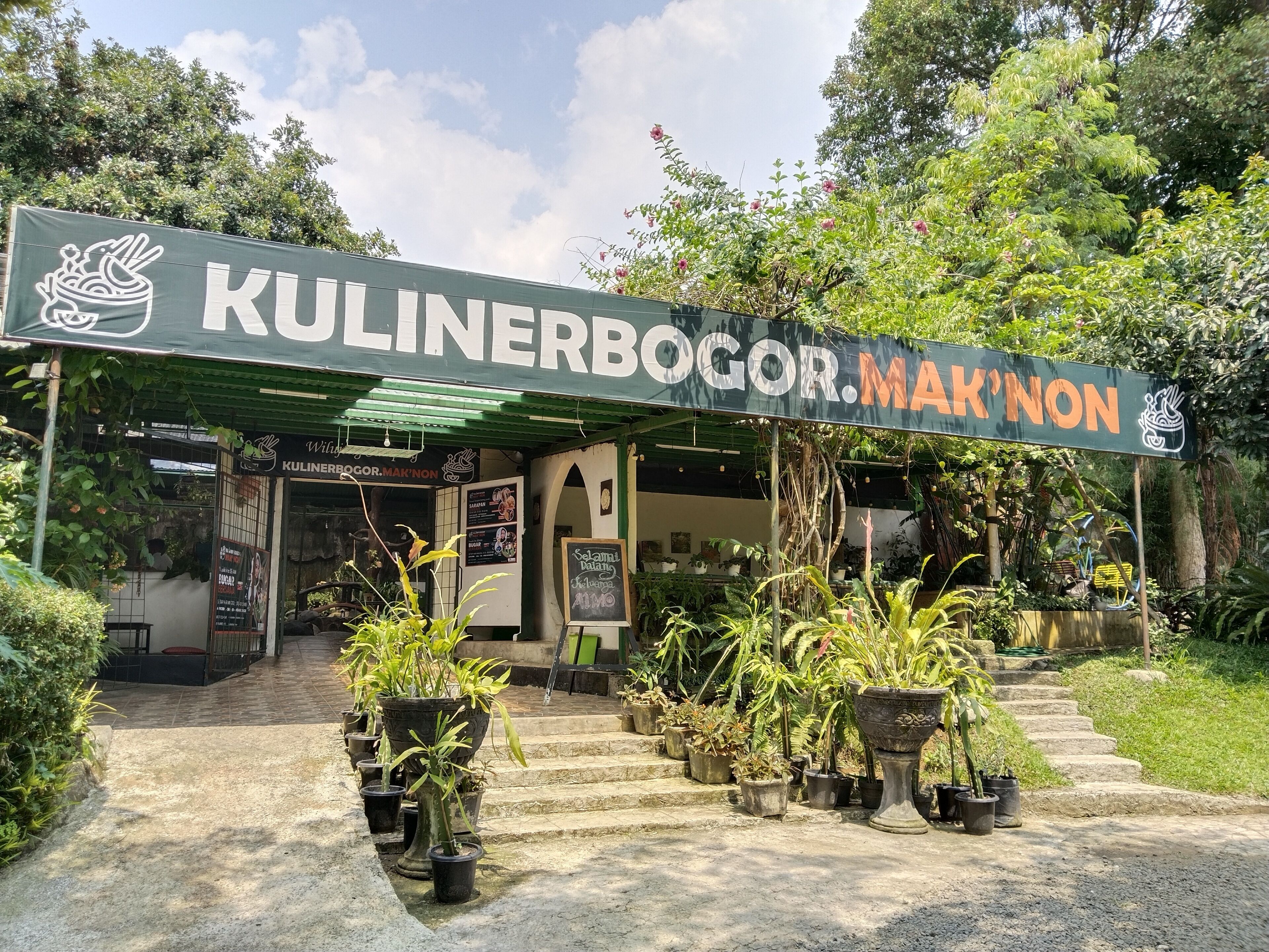 A storefront with a sign reading "KULINERBOGOR.MAK'NON" and a variety of potted plants in front.