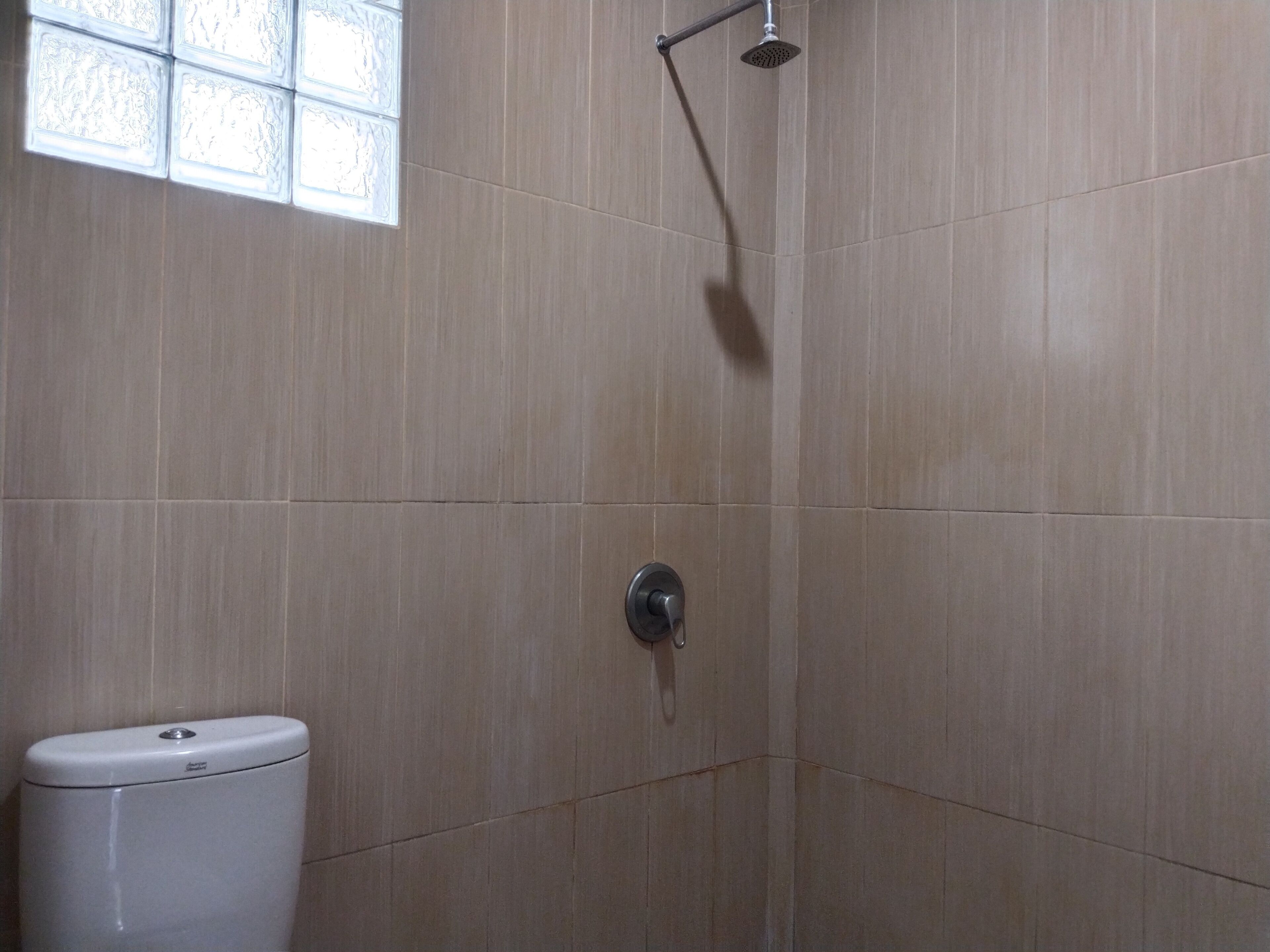 Une salle de bain avec une douche, des toilettes et une fenêtre.