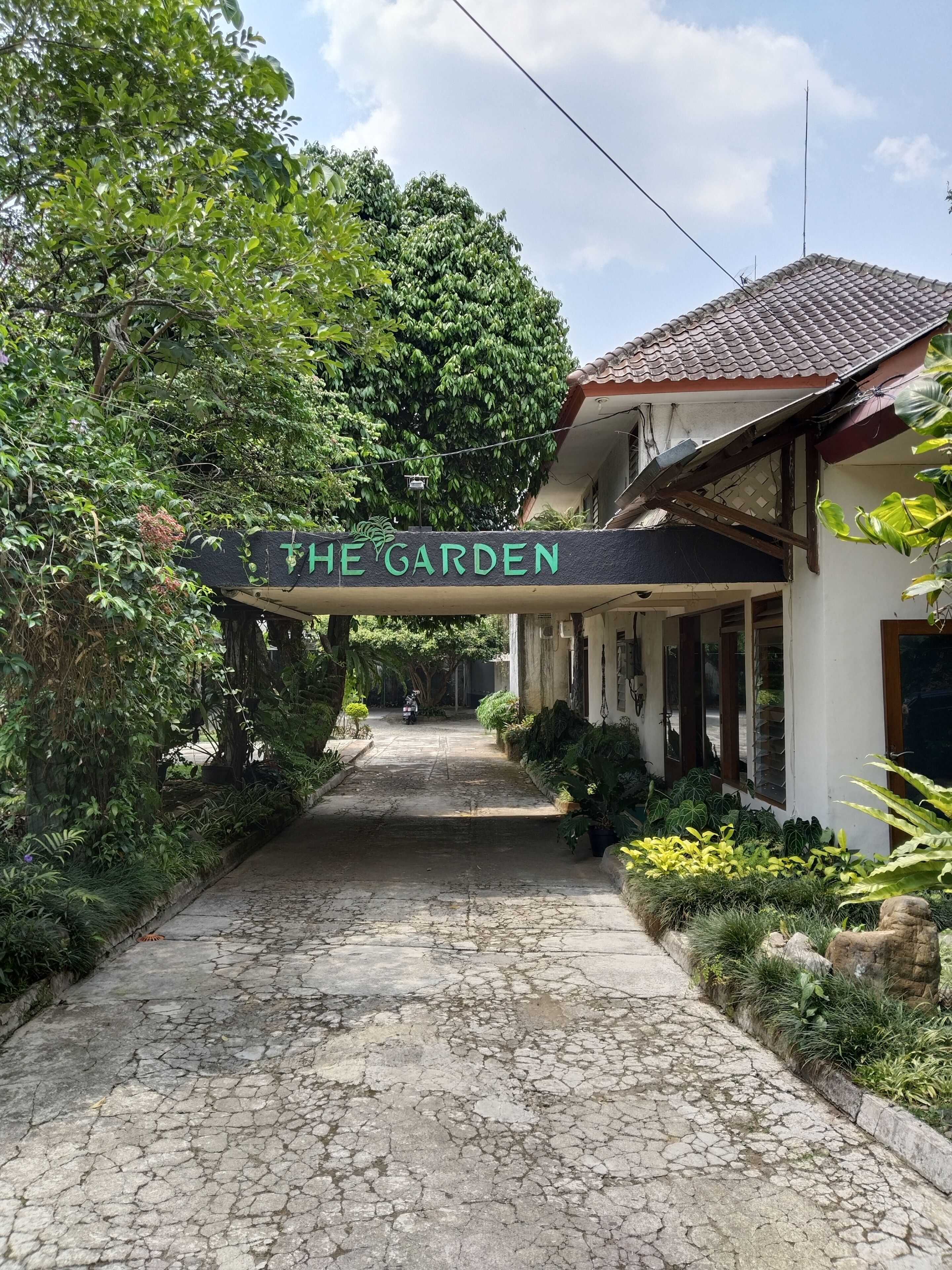 Un sendero lleva a un edificio con un letrero que dice 'THE GARDEN'.