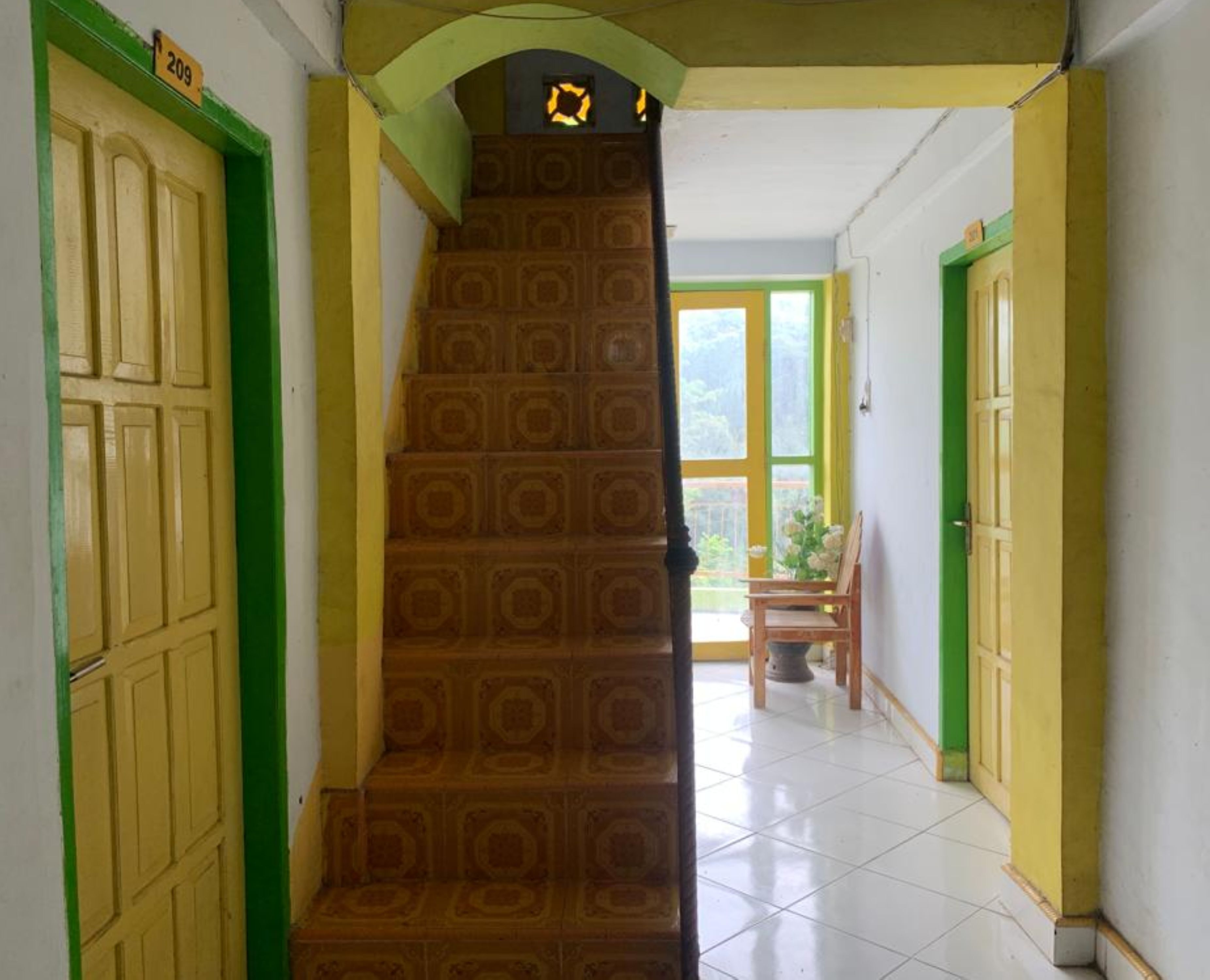 Uma escadaria com um desenho padronizado leva a um quarto com janela e uma cadeira.
