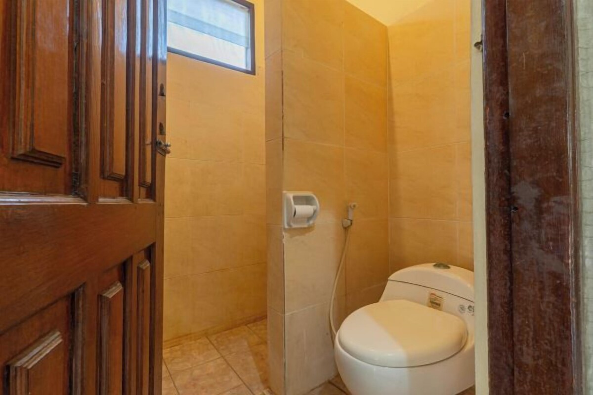 A small bathroom with a toilet, a towel rack, and a wooden door.