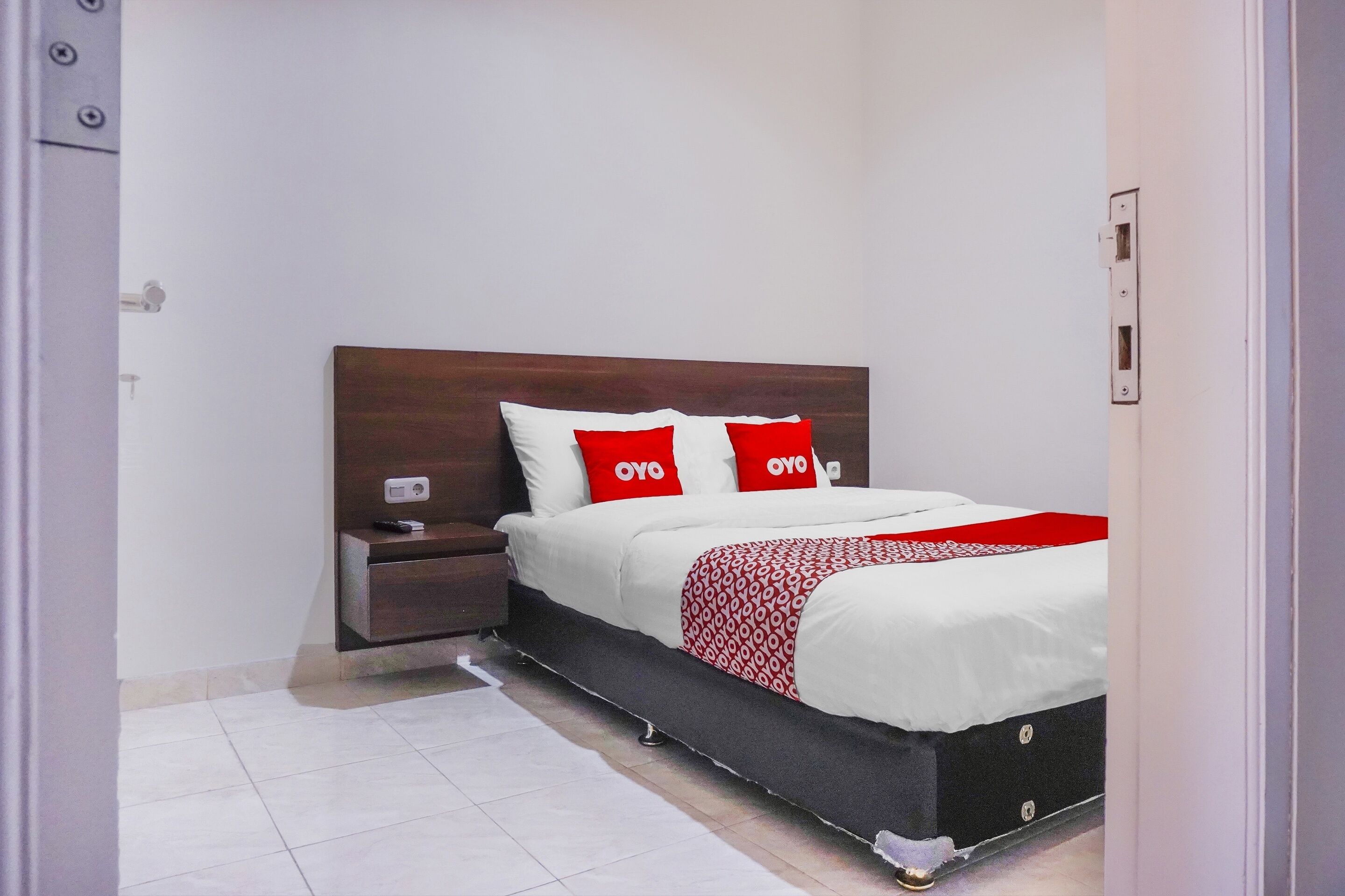 Une chambre bien rangée, avec un lit, une table de chevet et un luminaire fixé au mur.
