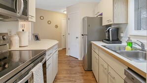 A modern kitchen with stainless steel appliances, a wooden countertop, and a built-in dishwasher.