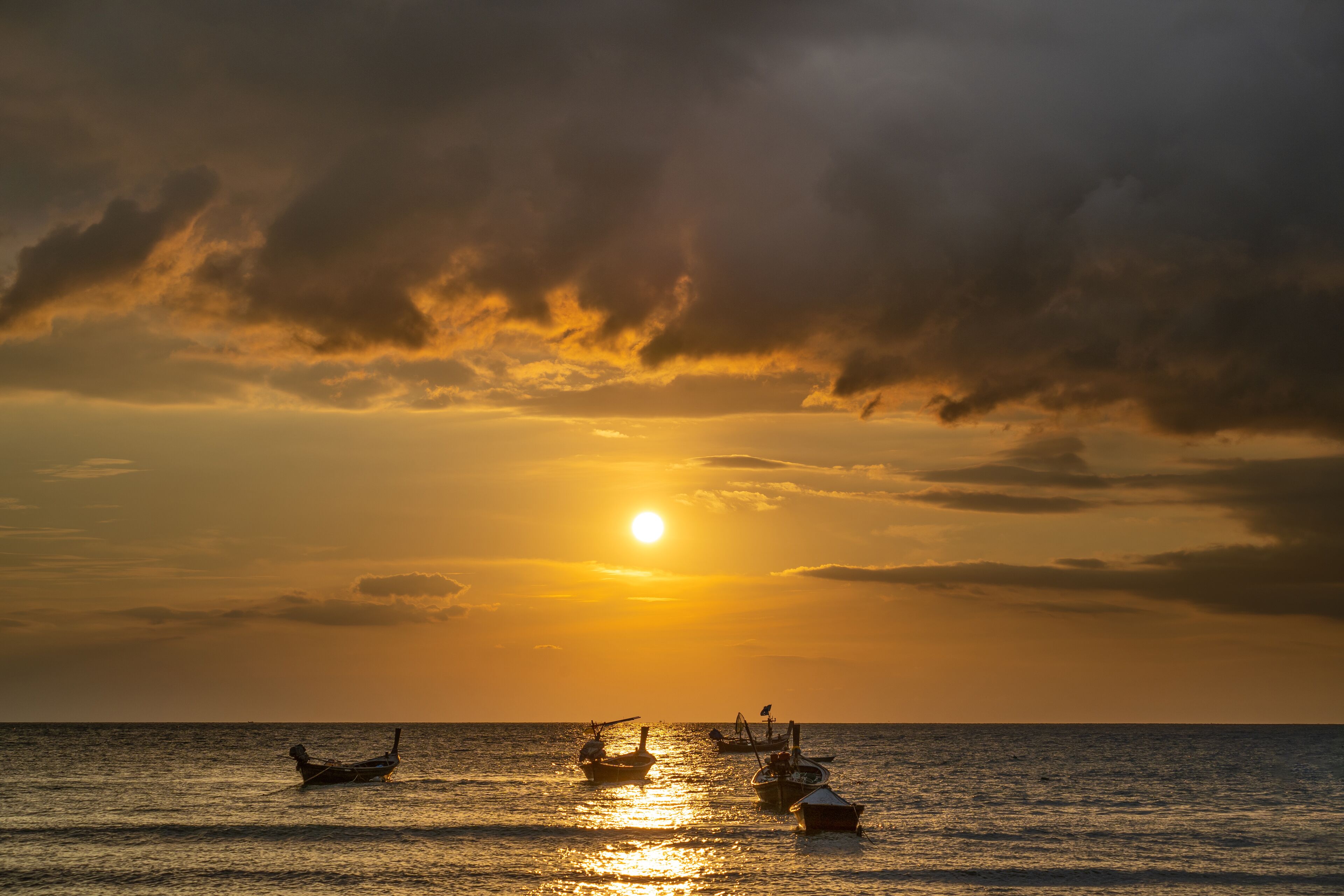 A sunset over the ocean with boats.