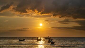 A sunset over the ocean with boats.
