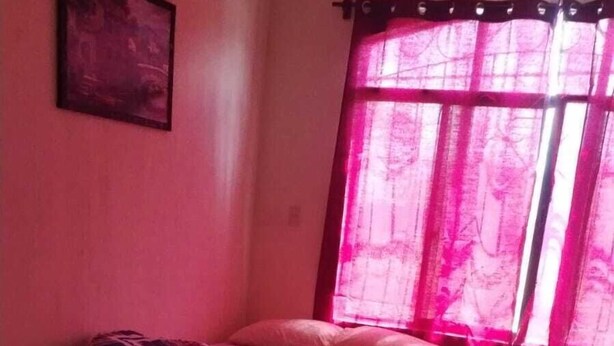A bedroom with two beds, a window with pink curtains, and a framed picture on the wall. - Hostal Maya Land (Santa Cruz del Quiché)
