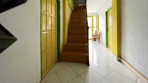 A hallway with tiled floors and green-framed doors.