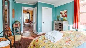 A bedroom with a bed, a dresser, a chair, and a door leading to another room. - The Shenandoah Suite: Private Balcony, Walkable (Staunton)