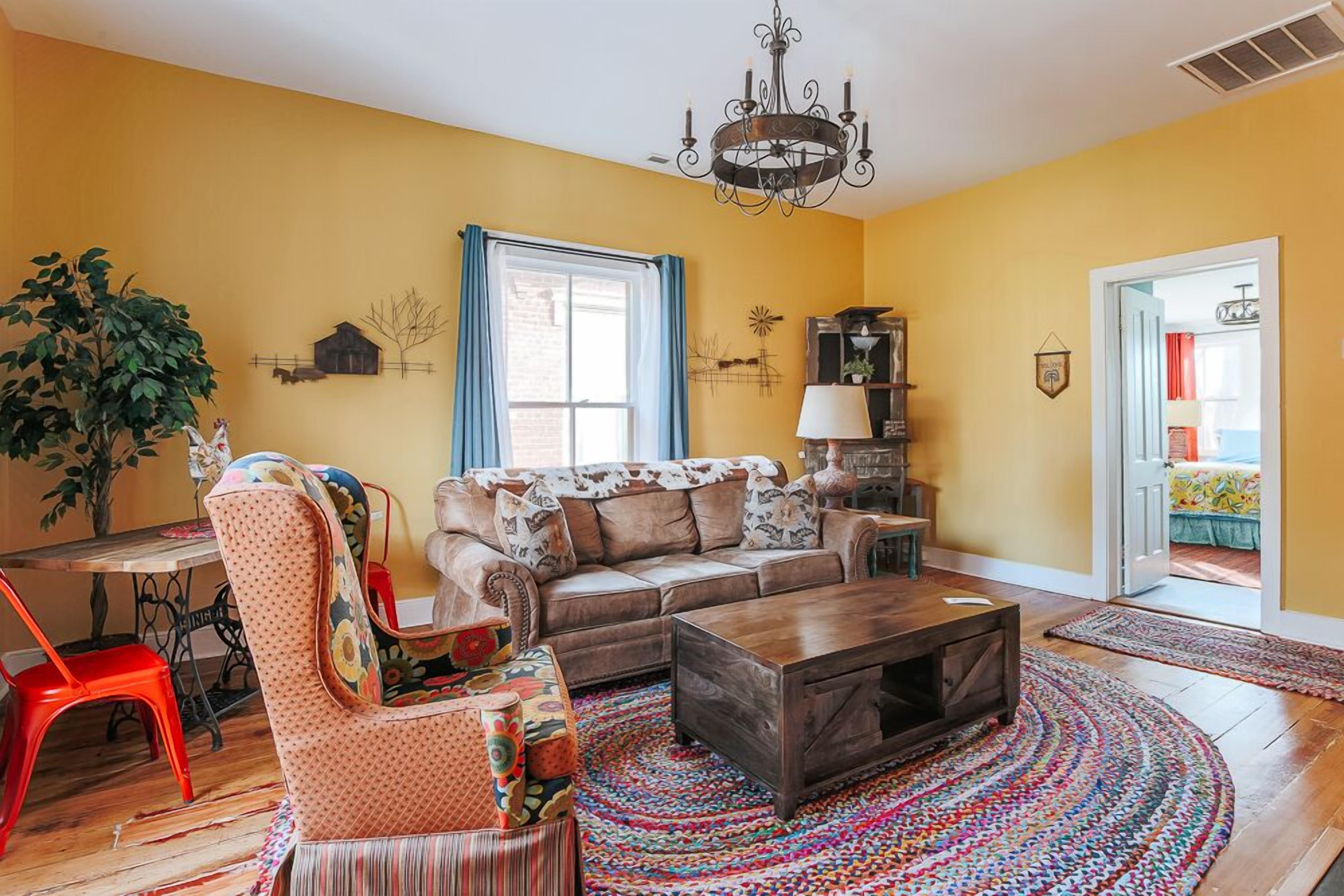 A living room with a sofa, armchair, coffee table, and a chandelier.