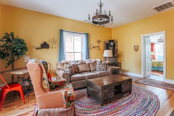 Una sala de estar con sofá, sillón, mesa de centro y candelabro.