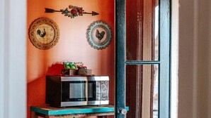 A doorway with a blue door, a microwave on a wooden stand, and decorative plates on the wall. - The Shenandoah Suite: Private Balcony, Walkable (Staunton)