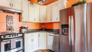 A kitchen with white cabinets, a stainless steel refrigerator, a stove, and a dishwasher. - The Shenandoah Suite: Private Balcony, Walkable (Staunton)