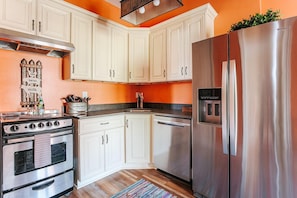 Una cocina con gabinetes blancos, un refrigerador de acero inoxidable y una estufa.
