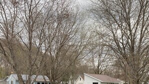 Une propriété au bord du lac, avec un petit bâtiment blanc, entourée d’arbres sans feuilles et bordée par une étendue d’eau calme.